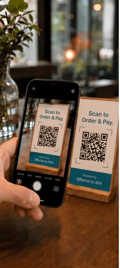 Cliente apontando a câmera do celular para um cartão QRwise sobre a mesa de madeira de um café
